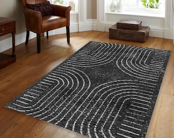 Könnte beinhalten: Ein schwarz-weißer Teppich mit einem geometrischen Muster aus geschwungenen Linien. Der Teppich liegt auf einem Holzboden in einem Wohnzimmer.