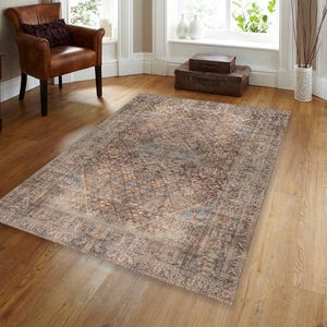 May include: A brown and beige patterned area rug with a faded, vintage look. The rug has a geometric design with a central diamond shape.