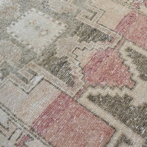 Puede incluir: Una alfombra vintage con un patr&oacute;n geom&eacute;trico en tonos beige, marr&oacute;n y rosa. La alfombra tiene un aspecto desgastado y descolorido, lo que le da un aspecto r&uacute;stico y antiguo.