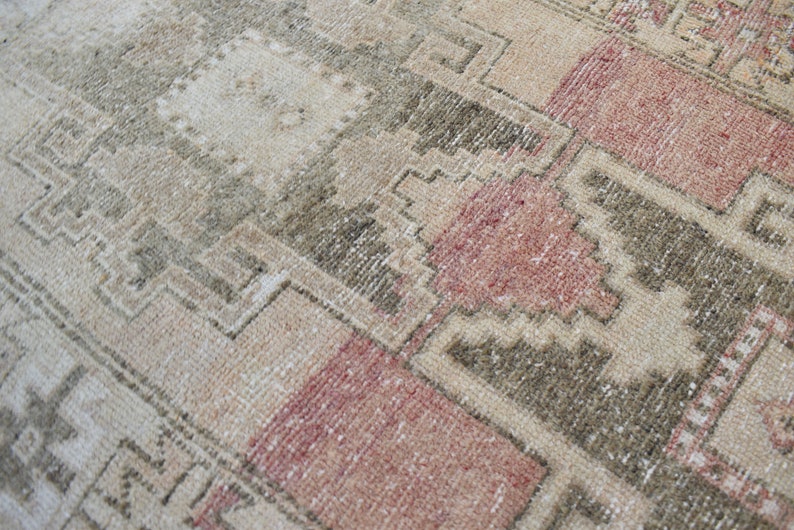 Puede incluir: Una alfombra vintage con un patr&oacute;n geom&eacute;trico en tonos beige, marr&oacute;n y rosa. La alfombra tiene un aspecto desgastado y descolorido, lo que le da un aspecto r&uacute;stico y antiguo.