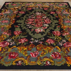May include: A black rug with a floral pattern in shades of red, pink, yellow, green, and blue. The rug has a detailed design with intricate details.