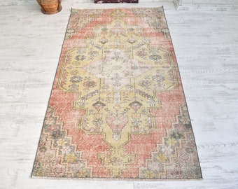 Puede incluir: Una alfombra vintage con un patrón intrincado descolorido en tonos de rosa, amarillo y verde. La alfombra tiene un aspecto desgastado y una apariencia desgastada y descolorida.