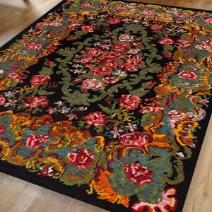 May include: A black rug with a floral pattern in shades of red, pink, yellow, green, and blue. The rug has a traditional design with intricate details.