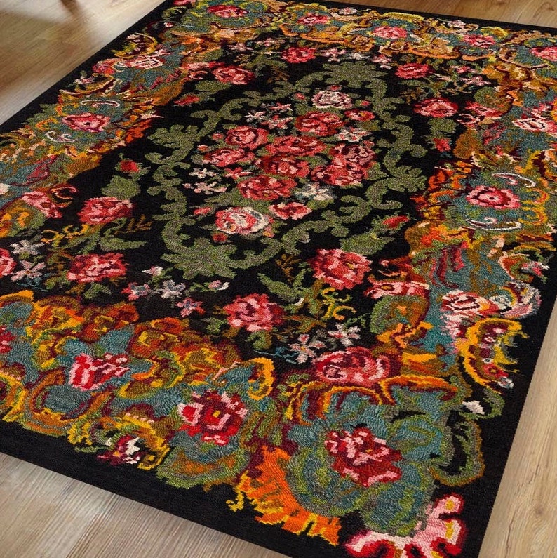 May include: A black rug with a floral pattern in shades of red, pink, yellow, green, and blue. The rug has a traditional design with intricate details.
