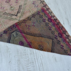 K&ouml;nnte beinhalten: Ein antiker t&uuml;rkischer Teppich mit einem geometrischen Muster in Rosa-, Braun- und Beiget&ouml;nen. Der Teppich hat einen Fransenrand und ist mit verschiedenen Texturen gewebt.