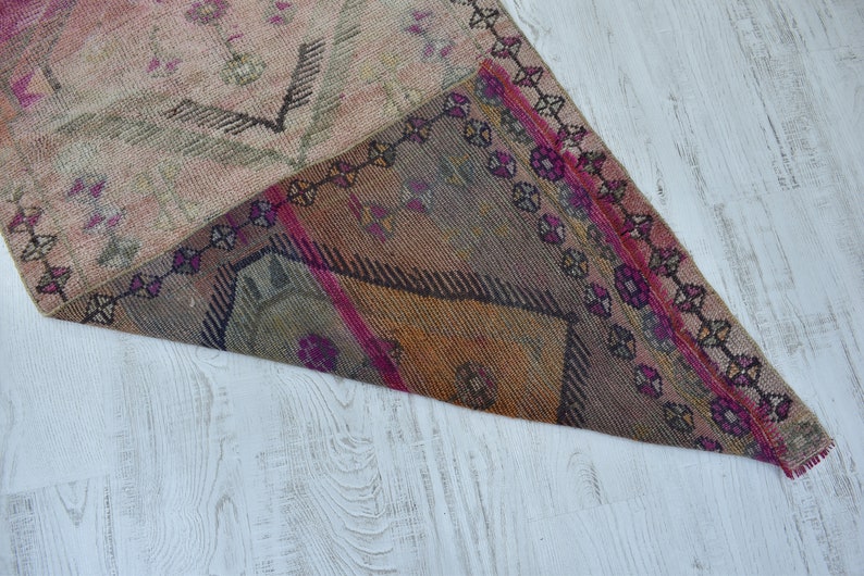 K&ouml;nnte beinhalten: Ein antiker t&uuml;rkischer Teppich mit einem geometrischen Muster in Rosa-, Braun- und Beiget&ouml;nen. Der Teppich hat einen Fransenrand und ist mit verschiedenen Texturen gewebt.