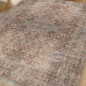 May include: A vintage-style rug with a faded, distressed look. The rug features a central diamond pattern with intricate floral details in shades of brown, blue, and beige.