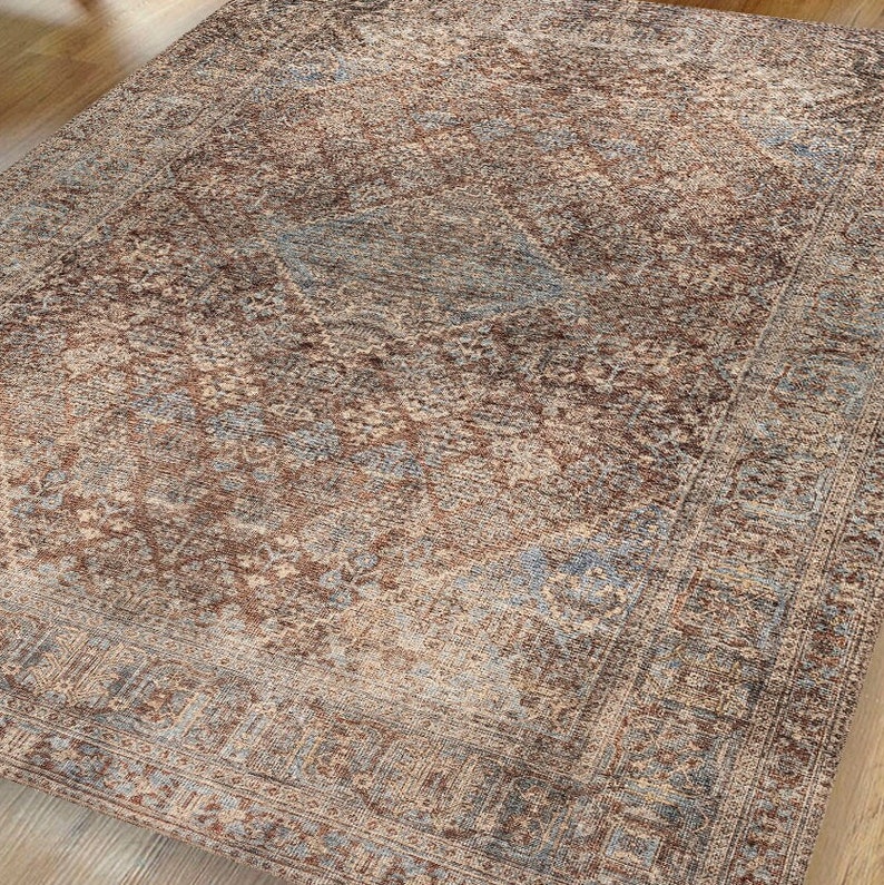 May include: A vintage-style rug with a faded, distressed look. The rug features a central diamond pattern with intricate floral details in shades of brown, blue, and beige.