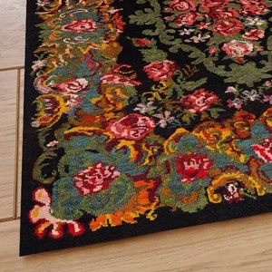 May include: A black rug with a floral pattern in shades of red, pink, yellow, and green. The rug has a detailed design with intricate floral motifs.