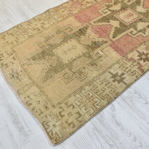 Puede incluir: Una alfombra turca vintage con un patr&oacute;n geom&eacute;trico en tonos beige, rosa y verde. La alfombra tiene un aspecto desgastado y es perfecta para a&ntilde;adir un toque de estilo bohemio a tu hogar.