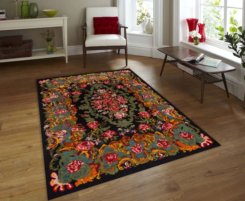 May include: A black area rug with a floral pattern in shades of red, orange, yellow, green, and blue. The rug has a detailed design with intricate floral motifs and a central medallion.