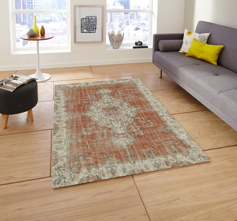 Puede incluir: Una alfombra de estilo vintage desgastada con un fondo rojo descolorido y un patr&oacute;n floral blanco. La alfombra tiene un aspecto desgastado y envejecido, lo que le da un atractivo r&uacute;stico y encantador.