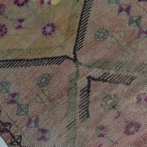 K&ouml;nnte beinhalten: Nahaufnahme eines rosafarbenen und braunen Teppichs mit schwarzem Rand. Der Teppich hat ein florales Design mit kleinen rosa Bl&uuml;ten und gr&uuml;nen Bl&auml;ttern.