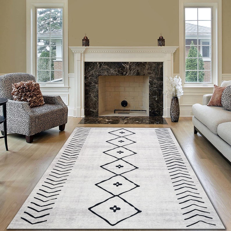 May include: A white and black geometric patterned rug with a diamond design. The rug is laid out on a hardwood floor in front of a fireplace.