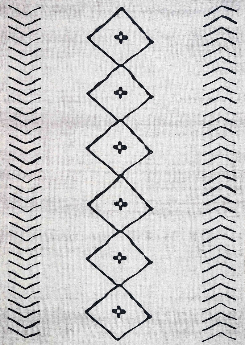 May include: A white rug with a black geometric pattern. The pattern features a series of diamonds with a plus sign in the center, and a border of chevron shapes.