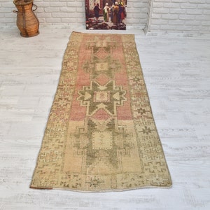 Puede incluir: Una alfombra de pasillo vintage con un patr&oacute;n geom&eacute;trico en tonos rosa, verde y beige. La alfombra tiene un aspecto desgastado y es perfecta para a&ntilde;adir un toque de estilo bohemio a cualquier habitaci&oacute;n.