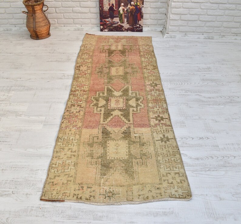 Puede incluir: Una alfombra de pasillo vintage con un patr&oacute;n geom&eacute;trico en tonos rosa, verde y beige. La alfombra tiene un aspecto desgastado y es perfecta para a&ntilde;adir un toque de estilo bohemio a cualquier habitaci&oacute;n.
