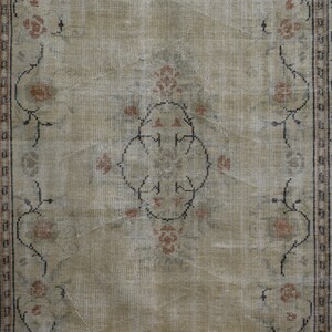 May include: A vintage rug with a beige background and a floral pattern in shades of brown and pink. The rug has a border with a geometric design.