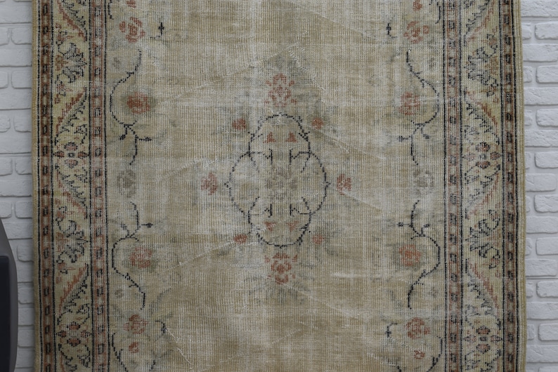 May include: A vintage rug with a beige background and a floral pattern in shades of brown and pink. The rug has a border with a geometric design.