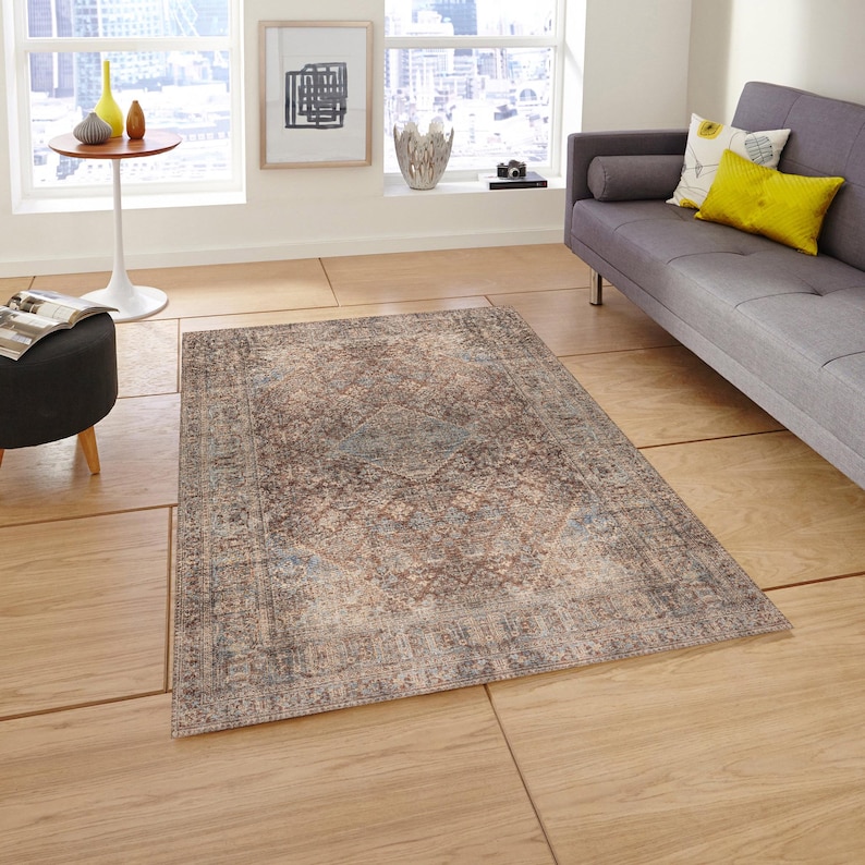 May include: A vintage-style rug with a brown, blue, and beige color scheme. The rug has a distressed look with a faded, intricate pattern.