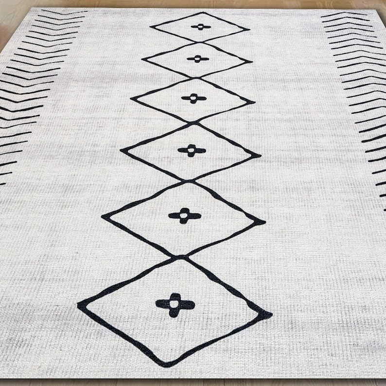 May include: A white rug with a black geometric pattern. The pattern features a series of diamonds with a plus sign in the center of each diamond.