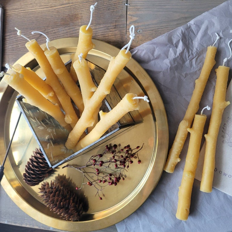grouping taper candles on the gold plate with natural objects, such as pine cone and rose hip,  birch branch beeswax taper candles display as a group looks great