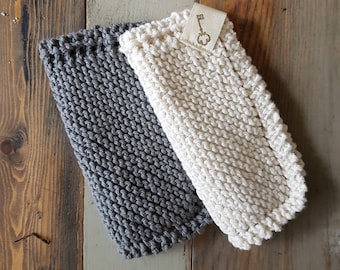 May include: Two knitted dishcloths, one gray and one white, with a small key-shaped tag attached to the white dishcloth.