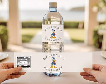 Puede incluir: Una botella de agua transparente con una etiqueta con el Pato Donald y el texto "MATTHEW'S BIRTHDAY". Una etiqueta separada con "Nutrition Facts" se sostiene debajo. La botella tiene una tapa gris.