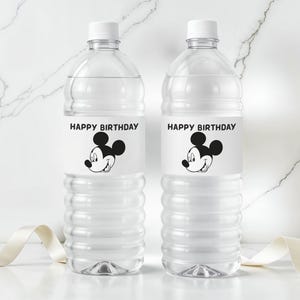 May include: Two clear plastic water bottles with white caps. Each bottle has a label with the text "HAPPY BIRTHDAY" above a black and white image of Mickey Mouse. A white ribbon is in the foreground.