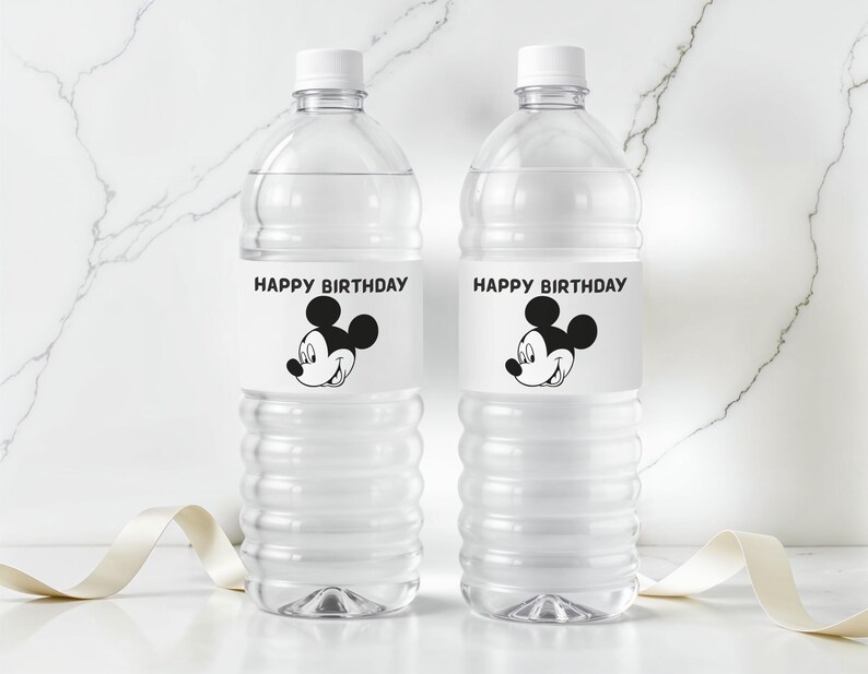 May include: Two clear plastic water bottles with white caps. Each bottle has a label with the text "HAPPY BIRTHDAY" above a black and white image of Mickey Mouse. A white ribbon is in the foreground.