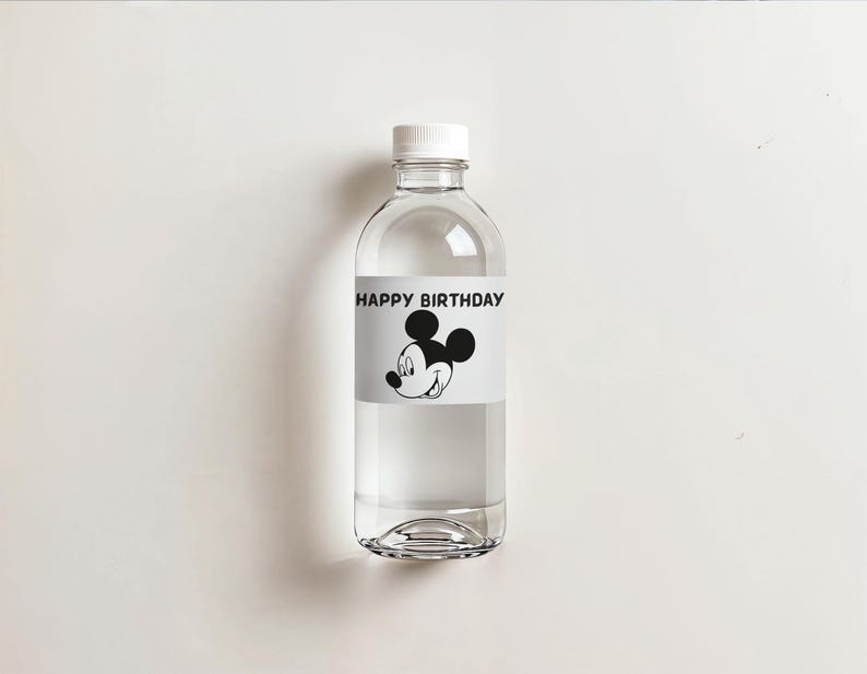 May include: A clear plastic water bottle with a white cap. The bottle has a label with the text "HAPPY BIRTHDAY" and a black and white image of Mickey Mouse. The bottle is filled with clear liquid and sits on a white surface.