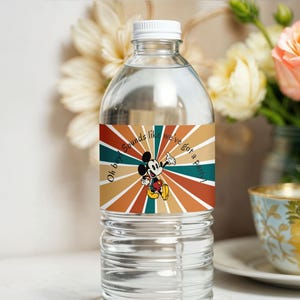 May include: A clear water bottle with a white cap and a colorful label featuring Mickey Mouse. The label has a retro design with radiating stripes in shades of brown, orange, and teal, and the text "Oh boy sounds like we've got a party!"