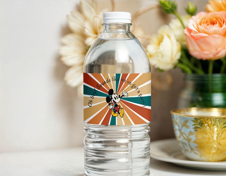 May include: A clear water bottle with a white cap and a colorful label featuring Mickey Mouse. The label has a retro design with radiating stripes in shades of brown, orange, and teal, and the text "Oh boy sounds like we've got a party!"