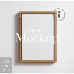 May include: A rectangular wooden frame mockup with the text "FRAME Mockup" in white. The frame is made of light brown wood and has a white interior. The image also includes the text "JPG PNG PSD" in the lower left corner and "ratio ratio ratio ISO A ratio ratio ratio" in the upper right corner.