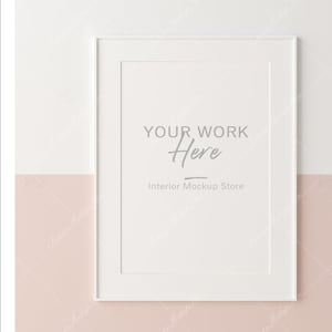 Puede incluir: Una maqueta de impresi&oacute;n art&iacute;stica enmarcada en blanco con el texto "YOUR WORK Here" e "Interior Mockup Store" en una pared de dos tonos. La pared est&aacute; dividida horizontalmente con una parte superior blanca y una inferior rosa rubor.
