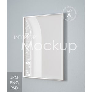 Könnte beinhalten: Ein silberner Rahmen-Mockup eines leeren Interior-Design-Posters. Das Poster hängt an einer hellblauen Wand. Der Text "INTERIOR MOCKUP" ist unter dem Poster sichtbar.