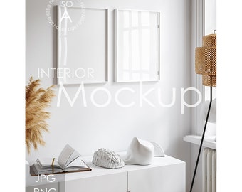 Può includere: Mockup di design d'interni bianco con due cornici bianche su una parete bianca, una cassettiera bianca con un libro e oggetti decorativi, e una lampada alta con un paralume intrecciato.
