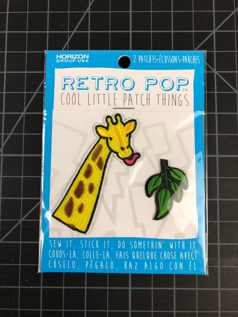 以下が含まれることがあります： アイロン接着できるパッチが2枚。1枚は茶色の斑点のある黄色いキリンで、ピンクの舌が出ています。もう1枚は緑の葉っぱです。パッケージには「レトロポップ クールリトルパッチシングス」と「縫い付けたり、貼り付けたり、何かしてね！」と書かれています。