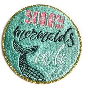 May include: A circular embroidered patch with a teal background and a gold glitter border. The text SORRY is in pink glitter, mermaids is in black cursive, and only is in white cursive. A black and teal mermaid tail is at the bottom left.