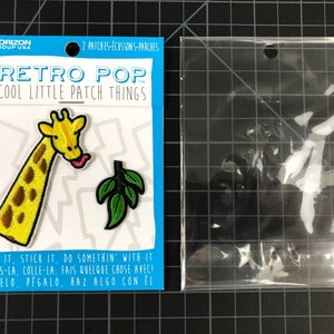 以下が含まれることがあります： アイロン接着式のワッペン2枚。1枚は葉っぱを食べているキリン、もう1枚は緑の葉っぱ。ワッペンは白いカードに貼られており、黒い文字で「レトロポップクールリトルパッチシングス」と「縫う、貼る、何かする」と書かれている。