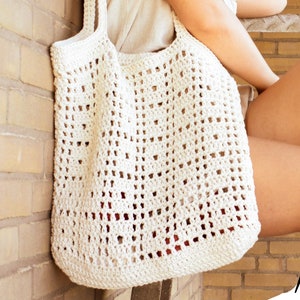 May include: A white crocheted tote bag with a square pattern. The bag is large and has a wide opening.