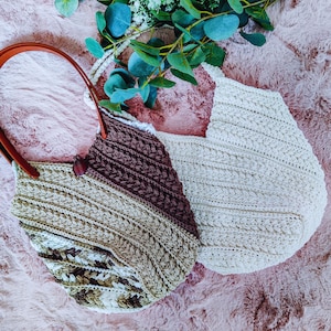 Puede incluir: Dos bolsos de mano de ganchillo hechos a mano. Un bolso es una mezcla de colores marrón, beige y crema con un asa de cuero marrón. El otro bolso es de color crema con un asa blanca. Ambos bolsos tienen un diseño tejido texturizado.