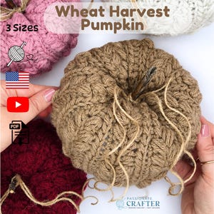 May include: A set of crocheted pumpkins in pink, tan, and dark red, featuring the text Wheat Harvest Pumpkin, 3 Sizes, and icons for yarn, a US flag, a YouTube play button, and a PDF file. Each pumpkin has a textured stitch and a twig stem.