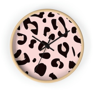 May include: A pink and black leopard print wall clock with a wooden frame.