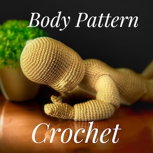 Könnte beinhalten: Häkelmuster für einen Puppenkörper. Die Puppe liegt auf einer Holzoberfläche. Die Puppe ist beige und hat einen gehäkelten Kopf und Gliedmaßen.