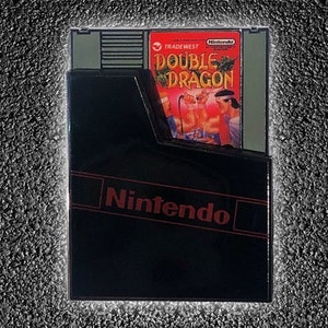 May include: A black Nintendo game cartridge with a red and white label that says "Double Dragon" and "Tradewest".
