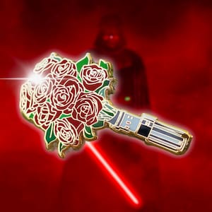 May include: A gold-colored pin featuring a bouquet of red roses with green leaves. The bouquet is attached to a lightsaber hilt. The background is red with a silhouette of Darth Vader and a red lightsaber.