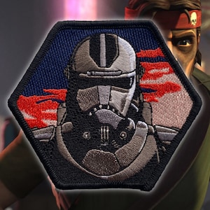 May include: A hexagonal embroidered patch featuring a gray and black Star Wars clone trooper with a red and white background.