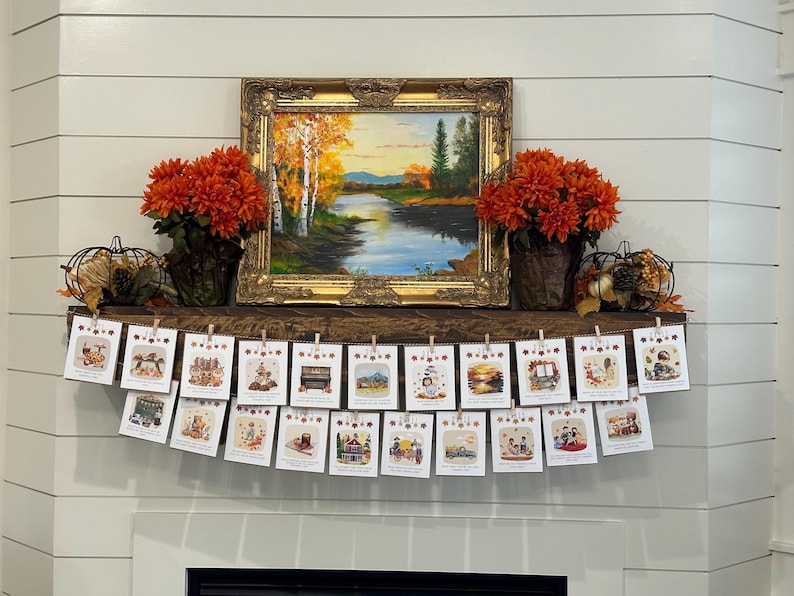 May include: A decorated mantel featuring a framed landscape painting, orange floral arrangements, and a banner of small cards. The cards are held by clothespins and depict various autumn-themed illustrations.