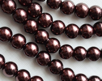 May include: A strand of dark brown pearl beads. The beads are round and have a high gloss finish.